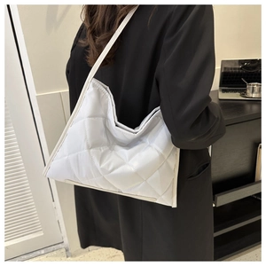 Detail view of the quilted texture and shoulder strap on a light grey puffer tote bag