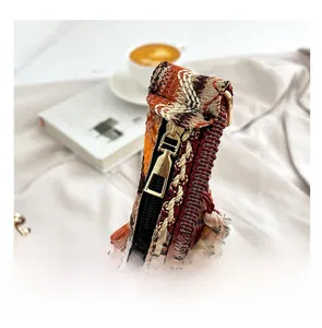 Detailed macro view of the smooth metal zipper and colorful woven texture on the saddle bag