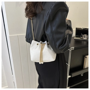 Detail der weißen Cord-Beuteltasche mit Perlenverzierung und goldener Kettenriemen