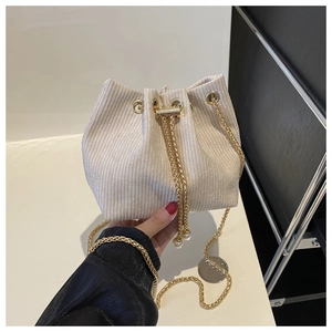 Detail der cremefarbenen Beuteltasche mit Cord-Textur und goldener Kettenschulterriemen