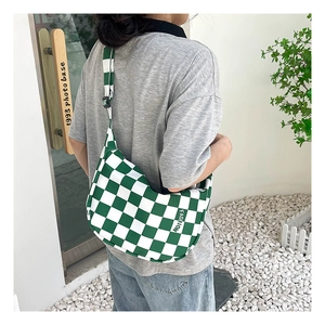 Mannequin portant un sac hobo en toile à damier vert et blanc dans un cadre extérieur