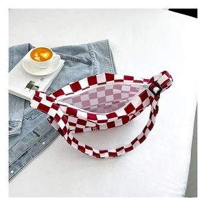 Vue détaillée de dessus d'un sac bandoulière en toile à damier rouge et blanc avec zip blanc