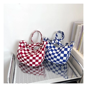 Détail de sacs fourre-tout en toile à damier rouge et bleu sur un chariot métal