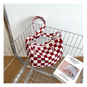 Détail du sac bandoulière croissant à damier rouge et blanc avec bandoulière large réglable