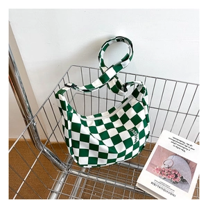 Gros plan du sac bandoulière en toile à damier vert avec sangle réglable dans un panier
