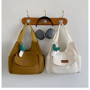 Détail de sacs cabas en toile avec poches avant, étiquettes en cuir et breloques oignon
