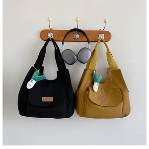 Détail de sacs fourre-tout en toile noir et jaune avec poches externes et breloques peluches