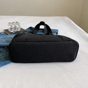 Detalle de la base reforzada resistente al desgaste de un bolso tote de lona negra