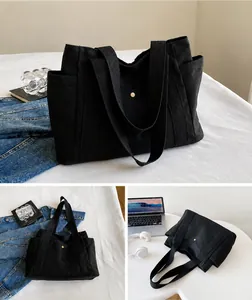 Vista detallada del bolso tote de lona negra grande con bolsillos y asas anchas
