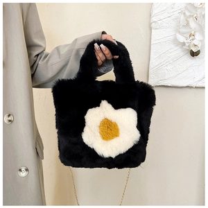 Detail of the plush black handbag featuring a floral pattern and golden metal chain strap