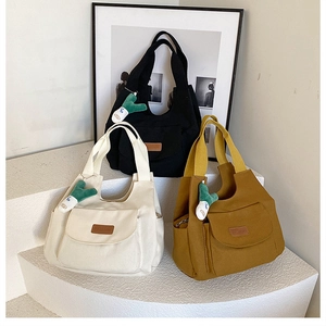 Trois sacs cabas en toile noir, beige et jaune avec charms en peluche verte