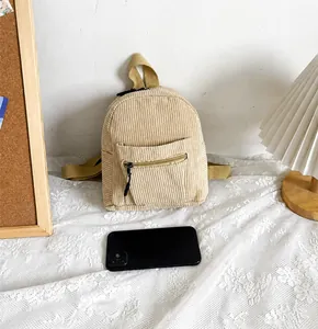 Detail of beige corduroy mini backpack showing texture and size compared to a phone