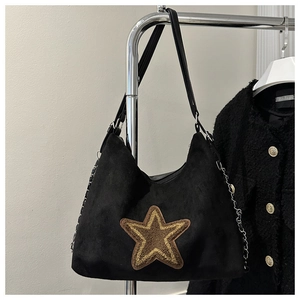 Detail van zwarte suède hobo tas met gele ster patch en metalen kettingriem