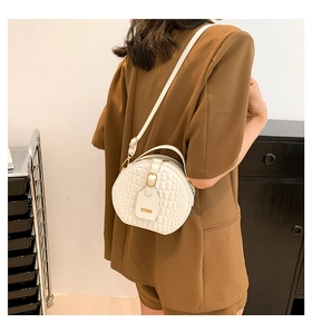 Detail of white semi-circle handbag with quilted crocodile texture and gold buckle