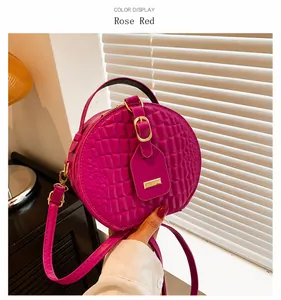 Dettaglio borsa rotonda rosa con trama a coccodrillo e finiture in metallo oro