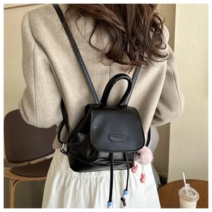 Detalle de una mini mochila negra con cierre de cordón y cuentas de colores