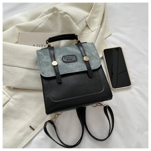 Detail showing contrast denim flap and leather body with fashion logo and gold hardware