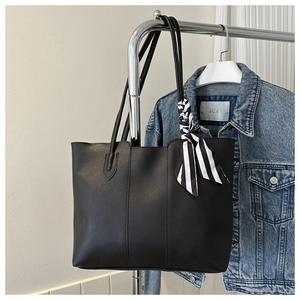 Detail einer schwarzen großen Tote Bag mit gestreiftem Seidenschal an einem Metallständer