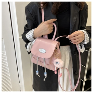 Detalle de mini mochila rosa de piel sintética con cordón de borlas y colgante de felpa