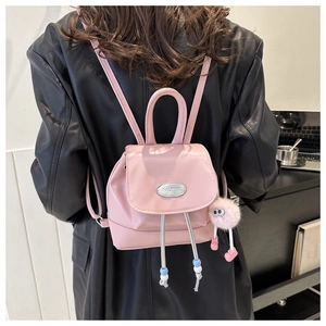 Detalle de la mochila de cuero sintético rosa con placa de logo y colgante de pompón