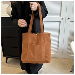 Gros plan sur le sac fourre-tout en velours côtelé caramel avec poche avant et bouton pression