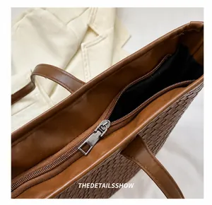 Detail of a smooth brown metal zipper on a woven tote bag with diamond texture