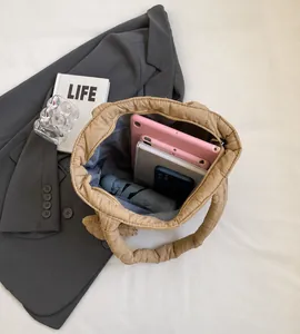 Interno spazioso della borsa trapuntata beige con tablet, cellulare e ombrello chiuso