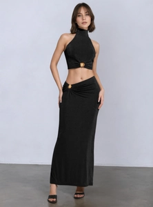 Detail view of the asymmetric black skirt featuring a golden seashell metal ornament