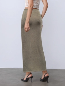Détail d'une jupe longue dorée à taille haute avec texture métallique et fente au dos