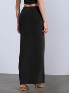 Detail view of a long black slim skirt with elegant draping and shell metal decor