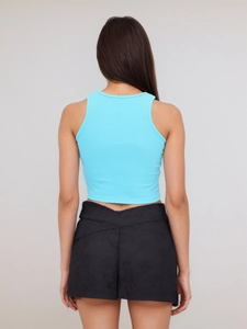 Detail of light blue ribbed knit crop top and black shorts with V-shaped cross waist
