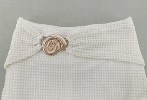 Gros plan sur un tissu en maille gaufrée blanche avec accessoire décoratif en métal doré