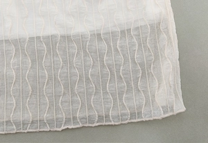 Detail of white mesh jacquard fabric with elegant vertical wave texture and fine edging