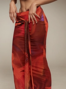 Dettaglio gonna a portafoglio in mesh con stampa astratta rosso-arancio e lunghi lacci