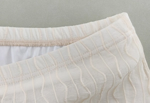 Detailed close-up of mesh jacquard fabric texture and elastic waistband of long skirt