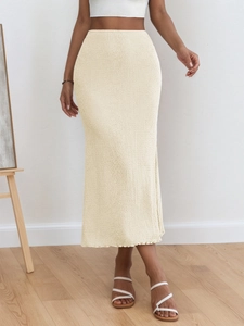 Detail of beige knit maxi skirt showing high-waisted fit and ribbed wavy edge texture