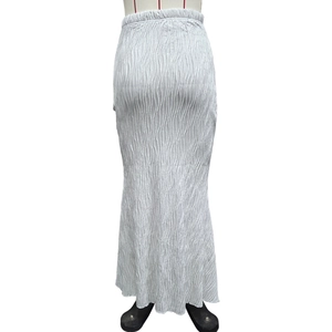 Detail view of the textured vertical pleated fabric on a white fishtail maxi skirt