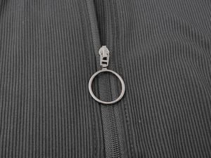 Close-up of circular metal ring zipper on dark grey ribbed knit bodysuit fabric