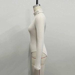 Detail of beige ribbed knit bodysuit featuring high collar and slim fit long sleeves