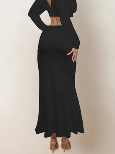Detail of black long sleeve backless crop top and high waist pleated maxi skirt set