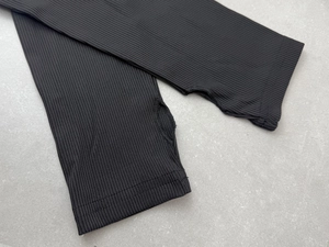 Detail of black ribbed knit arm sleeves featuring thumb holes and reinforced stitching