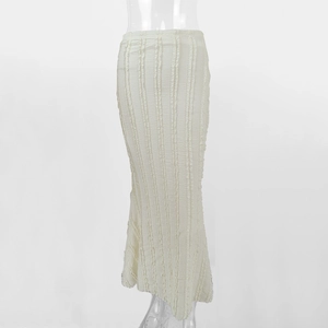 Détail d'une jupe sirène en tricot crème avec plis verticaux et texture frangée fine