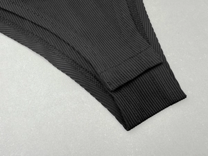 Close-up of black ribbed knit bodysuit fabric showing high-quality stitching detail