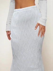 Detail shot of the vertical wavy pleat texture and elastic waistband of white long skirt