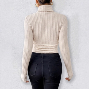 Detail showing the vertical ribbed texture of the beige slim-fit knit turtleneck bodysuit