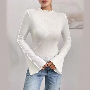 Detail showing ribbed white long-sleeve top with lettuce edge trim and asymmetric seams