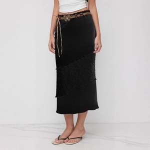 Détail de jupe plissée noire avec dentelle et ceinture tressée à boucle papillon