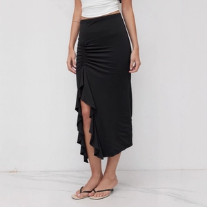 Detail of high waisted black ruched skirt with asymmetrical ruffle hem and side slit