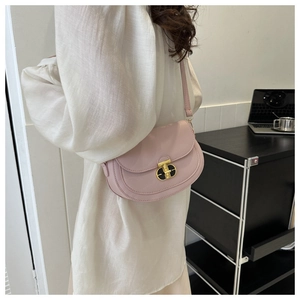 Detail of soft pink saddle bag with golden metal twist lock and slim shoulder strap