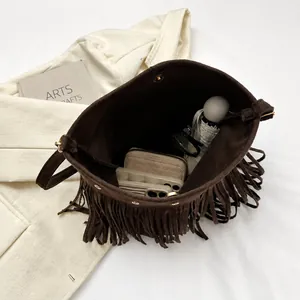Macro shot of dark brown tassel bucket bag showing large interior capacity with essentials